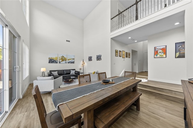 dining area with a towering ceiling and light hardwood / wood-style flooring