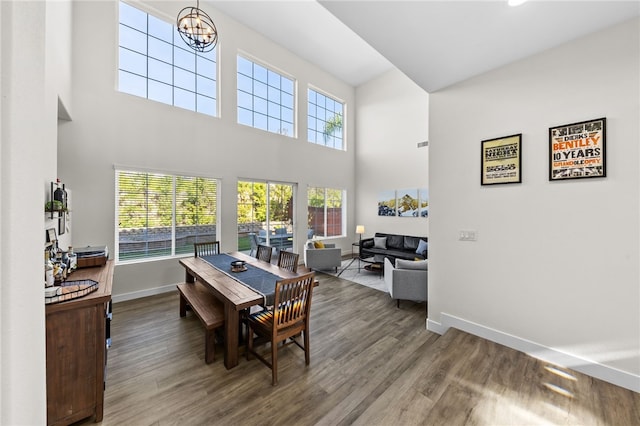 dining room with an inviting chandelier, a towering ceiling, and wood-type flooring