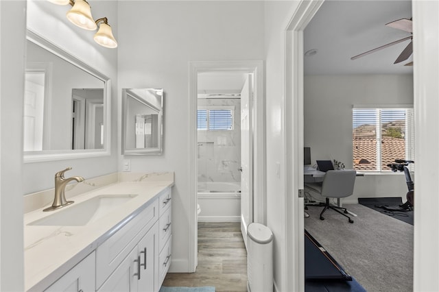 full bathroom with toilet, vanity, tiled shower / bath combo, ceiling fan, and hardwood / wood-style floors