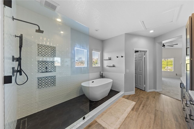 bathroom with wood-type flooring, plus walk in shower, tile walls, and vanity