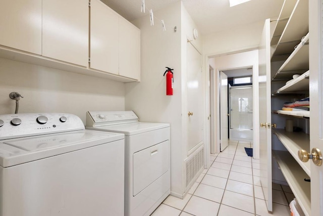 laundry area with light tile patterned flooring, cabinets, and washer and clothes dryer