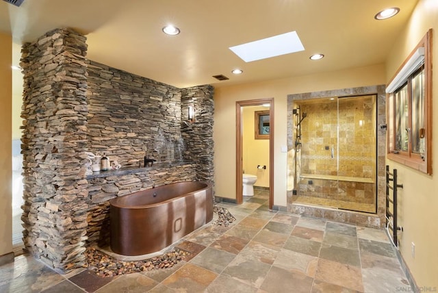 bathroom with a skylight, shower with separate bathtub, and toilet