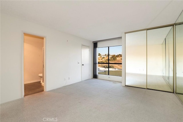 unfurnished bedroom featuring connected bathroom, carpet, and a closet