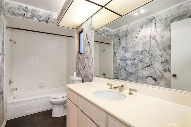 full bathroom featuring tiled shower / bath, vanity, and toilet