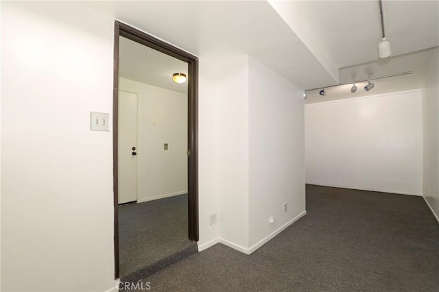 empty room featuring track lighting and dark carpet