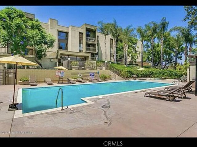community pool with fence and a patio area