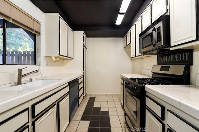 kitchen with tile counters, white cabinetry, tile patterned floors, a sink, and appliances with stainless steel finishes