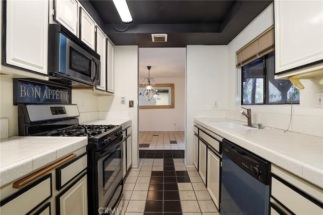 kitchen featuring stainless steel appliances, tile counters, visible vents, and a sink