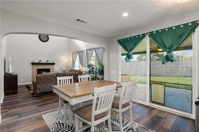 dining space featuring a tile fireplace and dark hardwood / wood-style flooring