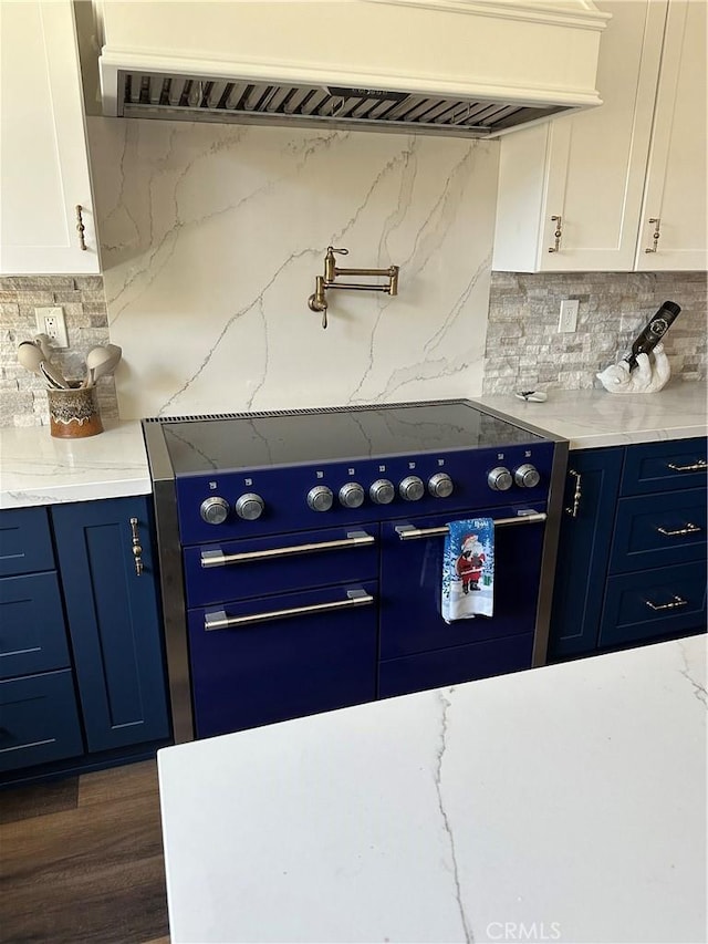 kitchen with exhaust hood, white cabinets, stove, light stone countertops, and backsplash