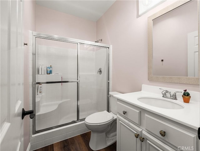 bathroom with a shower with door, wood-type flooring, vanity, and toilet