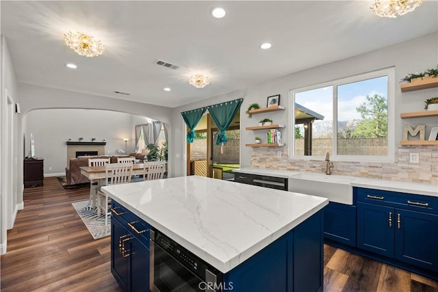 kitchen featuring blue cabinets, sink, light stone countertops, and a kitchen island