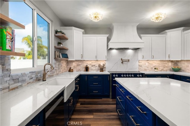 kitchen with premium range hood, blue cabinetry, white cabinets, and light stone counters