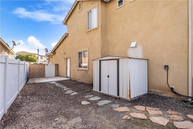 rear view of house featuring a storage unit