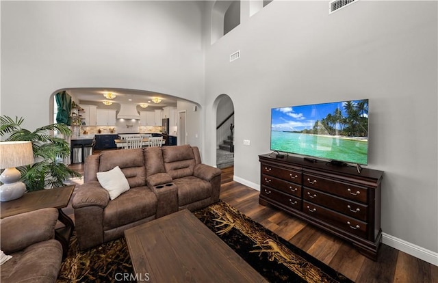 living room with a high ceiling and dark hardwood / wood-style floors