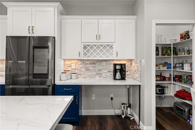 kitchen featuring dark hardwood / wood-style floors, white cabinetry, stainless steel fridge, light stone countertops, and blue cabinetry