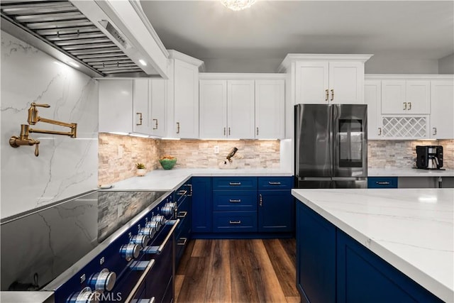 kitchen featuring blue cabinets, custom exhaust hood, white cabinets, and stainless steel refrigerator