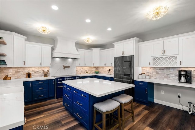 kitchen with white cabinetry, range, premium range hood, and blue cabinets