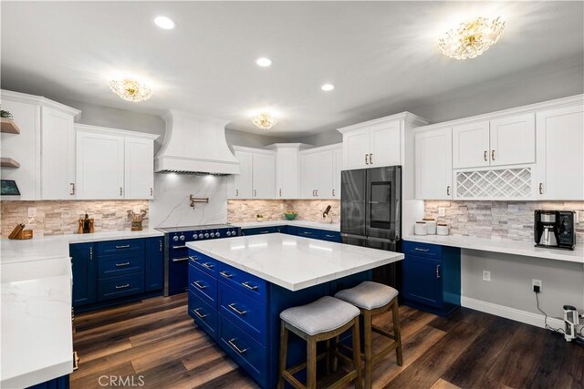 kitchen featuring blue cabinets, white cabinetry, premium range hood, and range