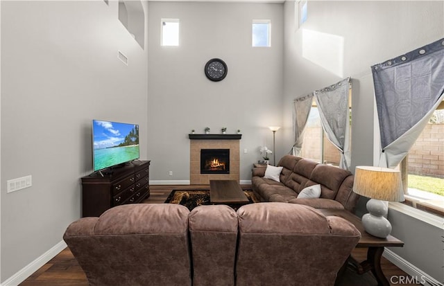 living room featuring a fireplace, dark hardwood / wood-style flooring, and a towering ceiling