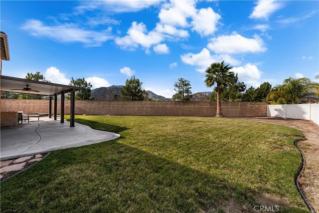 view of yard with a mountain view, a patio, and ceiling fan