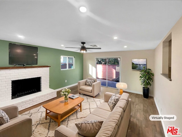 living room featuring ceiling fan, a fireplace, and light wood-type flooring