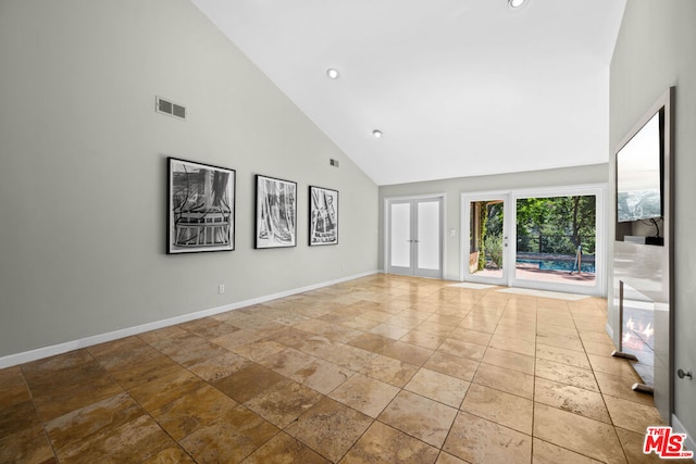 unfurnished living room featuring french doors and high vaulted ceiling