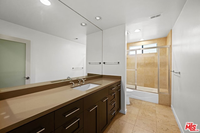 full bathroom featuring vanity, combined bath / shower with glass door, and toilet