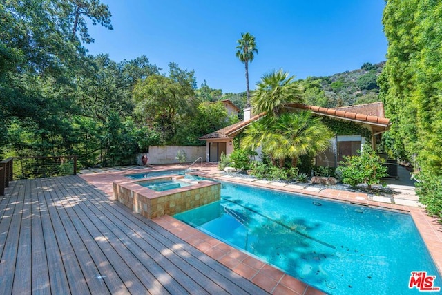 view of pool with an in ground hot tub and a deck