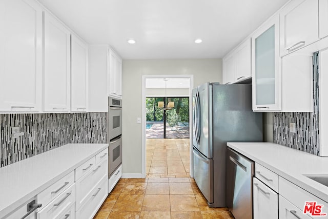 kitchen with white cabinetry, backsplash, light tile patterned floors, and appliances with stainless steel finishes