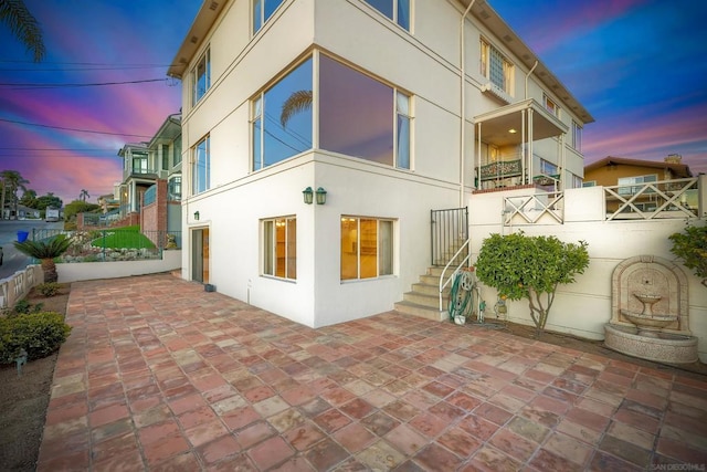 property exterior at dusk featuring a patio area