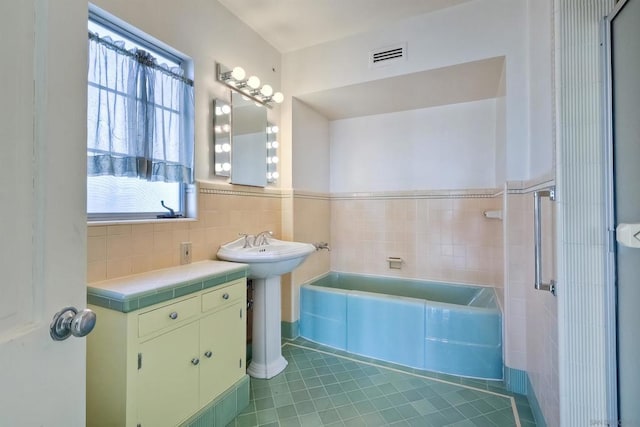 bathroom with plenty of natural light, tile patterned floors, and a tub to relax in