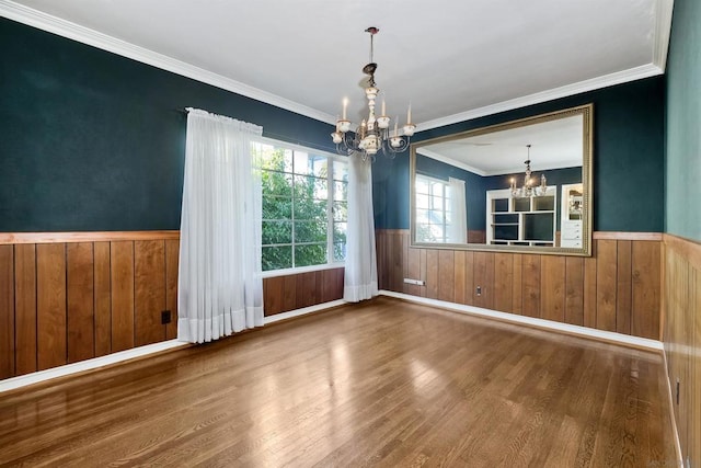 unfurnished dining area featuring an inviting chandelier, crown molding, and wood-type flooring