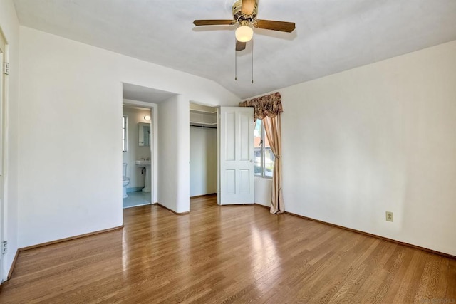 unfurnished bedroom with hardwood / wood-style flooring, ensuite bath, ceiling fan, vaulted ceiling, and a closet