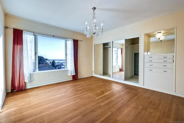 unfurnished bedroom featuring a chandelier, light hardwood / wood-style floors, and a closet