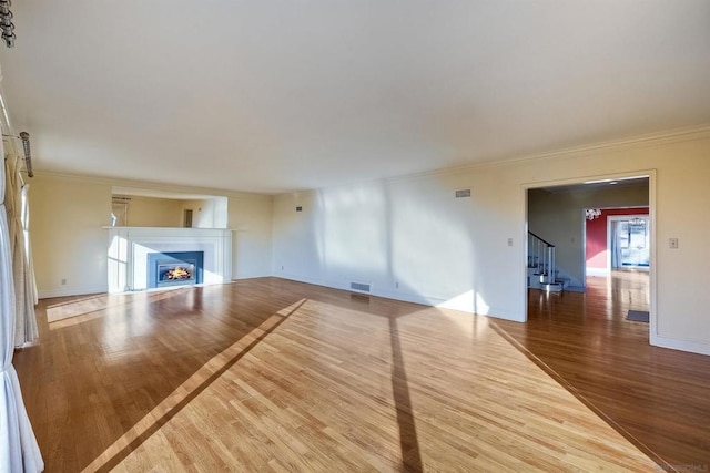 unfurnished living room featuring crown molding and hardwood / wood-style floors