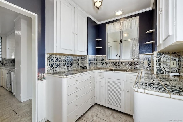 kitchen featuring sink, light tile patterned floors, ornamental molding, decorative backsplash, and white cabinets