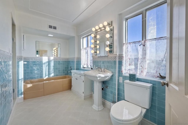 bathroom featuring tile walls, tile patterned floors, toilet, and a bathing tub