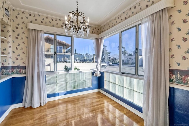 unfurnished dining area with hardwood / wood-style floors, a notable chandelier, and ornamental molding