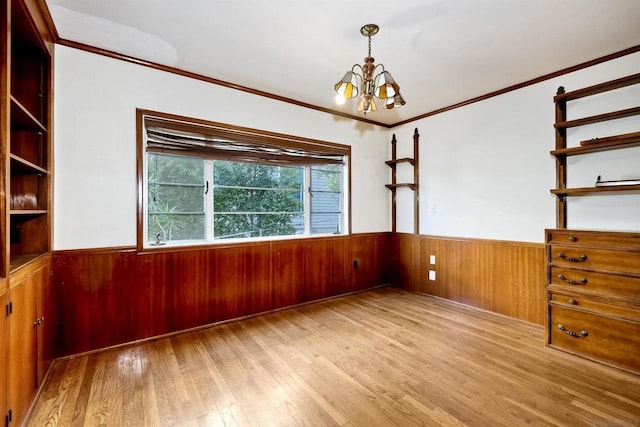 unfurnished room with an inviting chandelier, ornamental molding, and light hardwood / wood-style floors