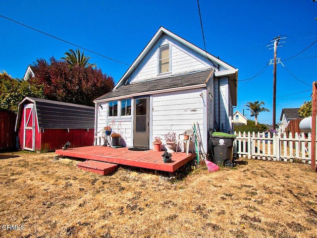 rear view of property featuring a wooden deck, a lawn, and a shed