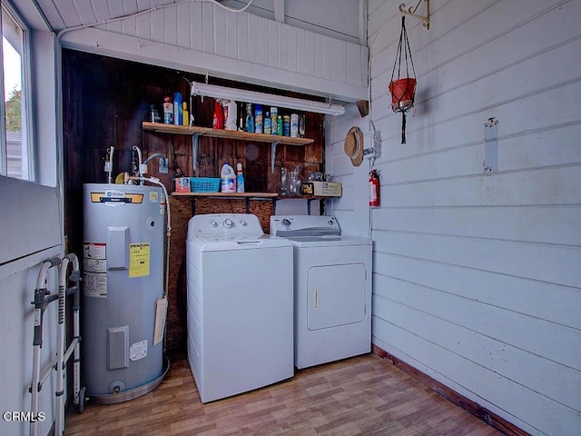 washroom with washer and dryer, electric water heater, light wood-type flooring, and wood walls