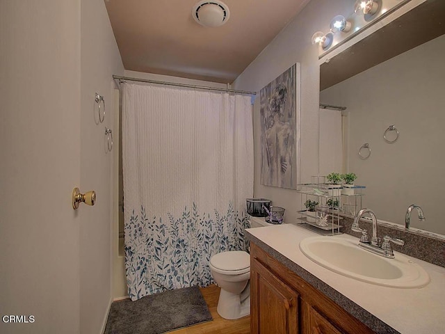 full bathroom with hardwood / wood-style flooring, shower / tub combo with curtain, vanity, and toilet