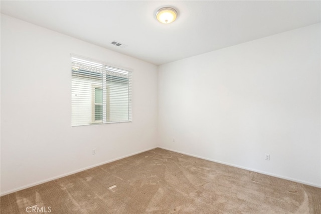 spare room featuring carpet, visible vents, and baseboards