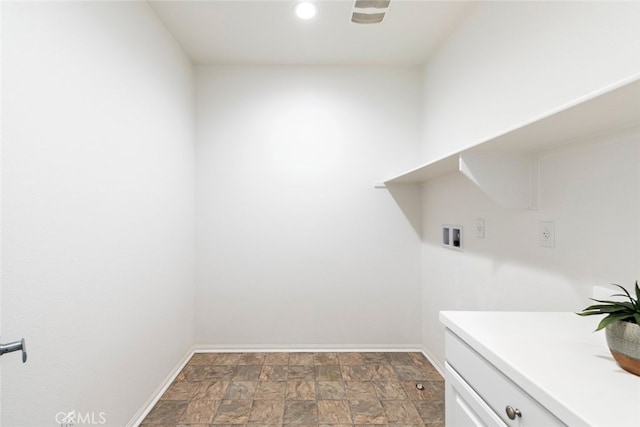 clothes washing area with cabinet space, stone finish flooring, baseboards, and washer hookup