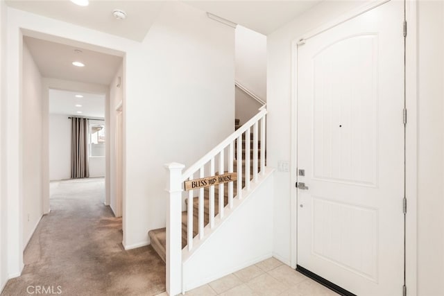 foyer featuring baseboards and light colored carpet