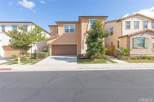 mediterranean / spanish home with driveway, an attached garage, a tiled roof, and stucco siding