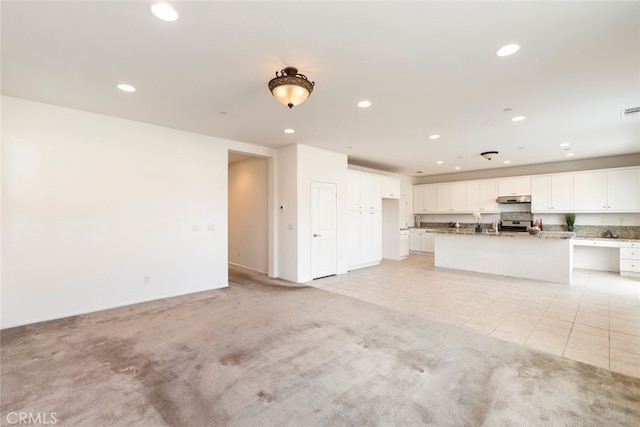 kitchen featuring light carpet, recessed lighting, white cabinets, and under cabinet range hood