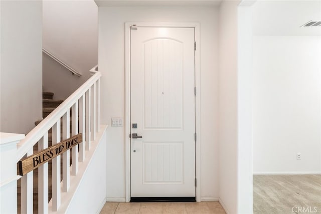 interior space featuring light carpet, stairway, baseboards, and visible vents