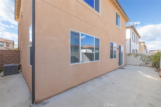 view of home's exterior featuring central air condition unit, stucco siding, fence, and a patio